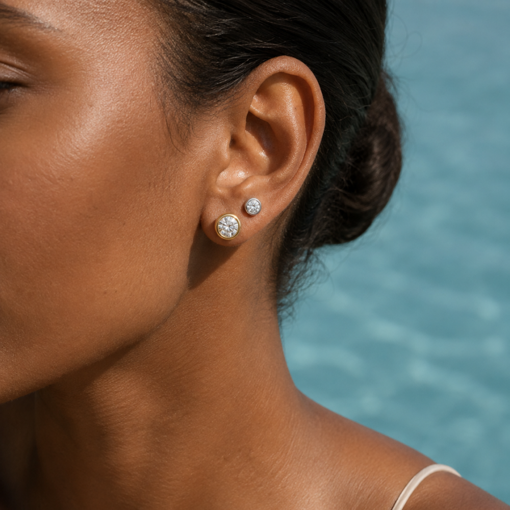 Two pairs of Vero bezel diamond studs worn on one ear, half carat above one carat
