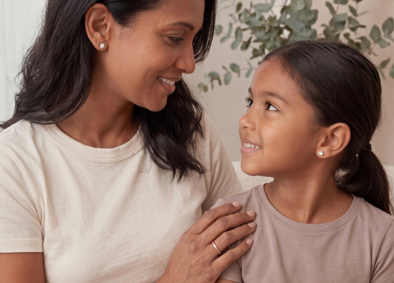 Mother and daughter sharing a moment wearing fine jewelry in soft natural light
