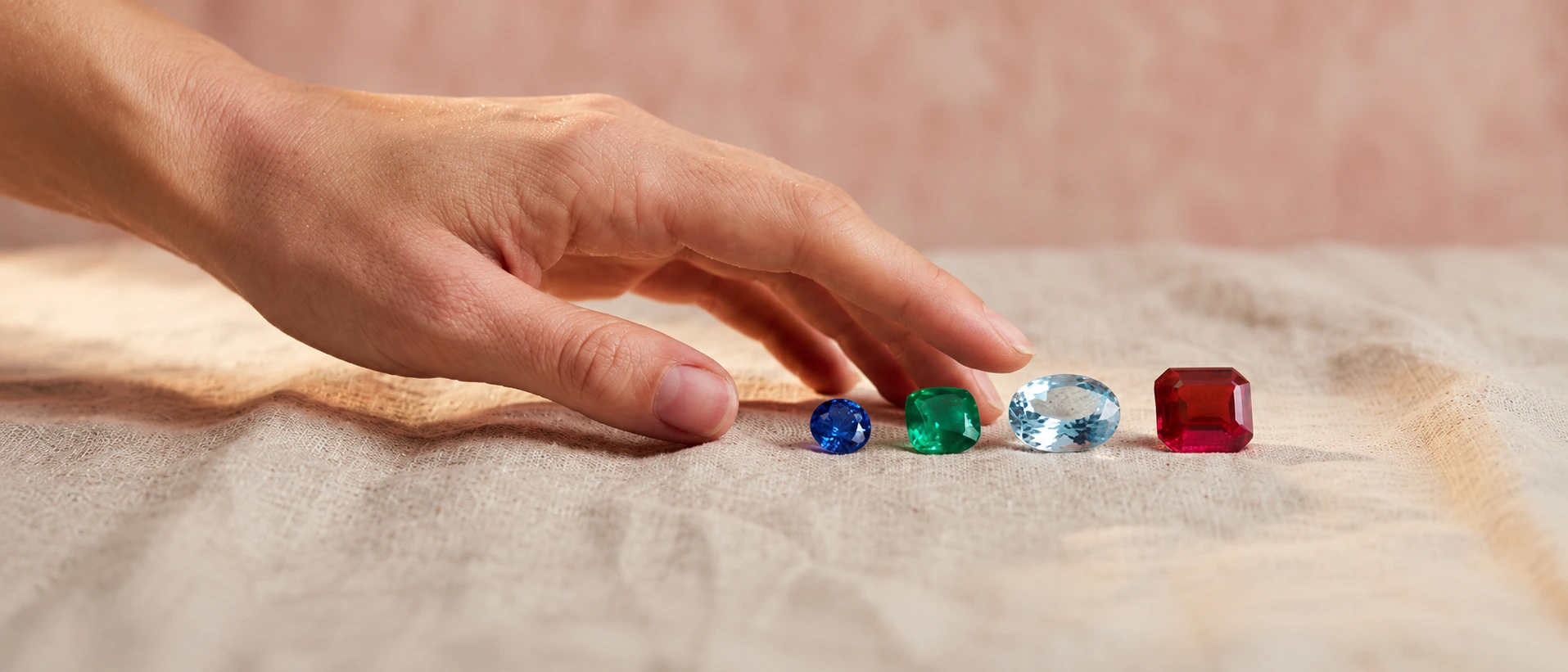 Hand wearing sapphire, emerald, and ruby engagement rings by SAMA — crafted with ethical gemstones