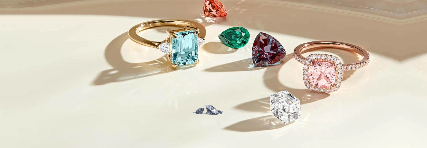 trio of sapphire, emerald, and ruby gemstone rings styled together on a soft neutral backdrop