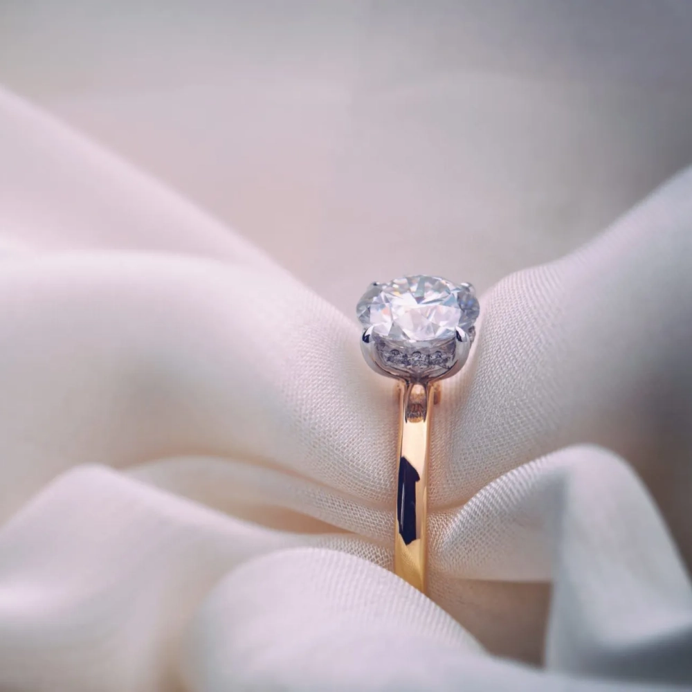 round-cut hidden halo engagement ring displayed on soft fabric