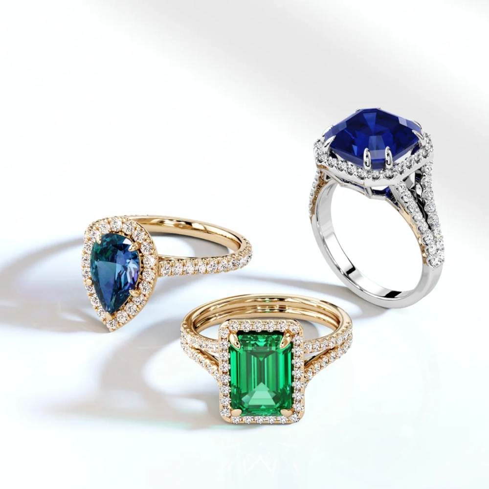 trio of blue sapphire and green emerald gemstone rings photographed on a clean background
