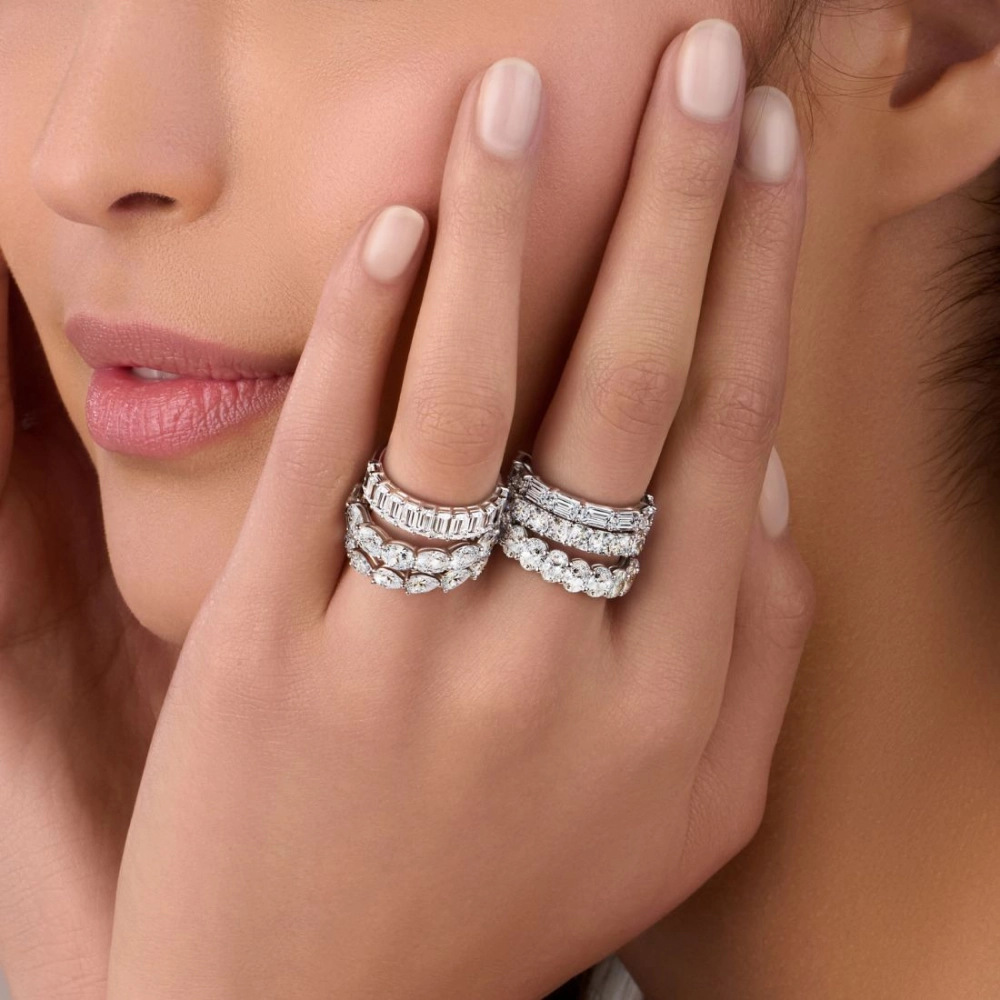 woman's hand wearing mixed stackable diamond eternity bands in a soft, warm portrait setting