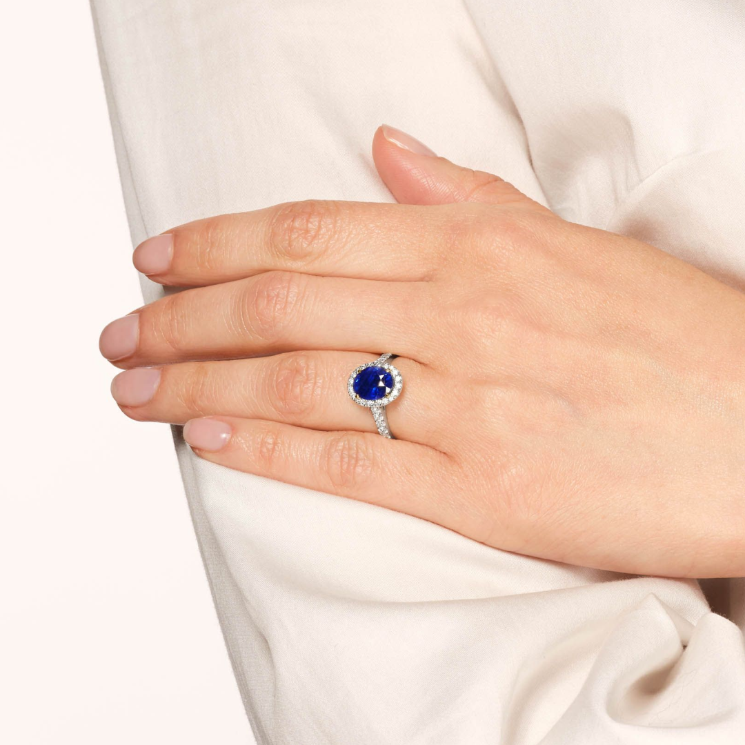 Blue sapphire halo engagement ring on woman's hand by SAMA