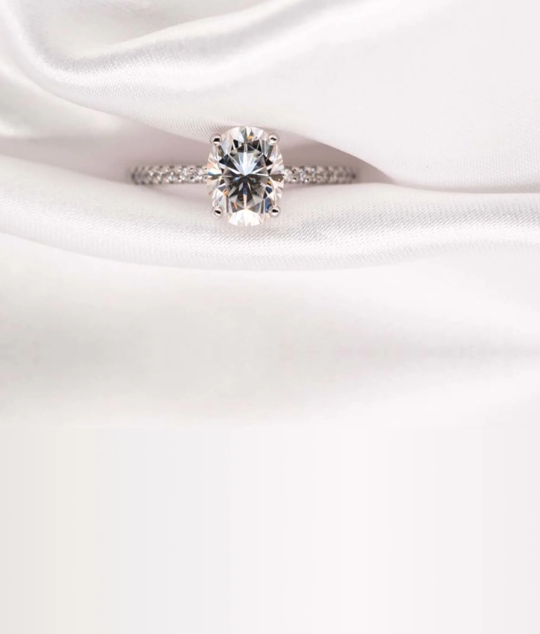 Oval-cut diamond engagement ring on satin fabric by SAMA