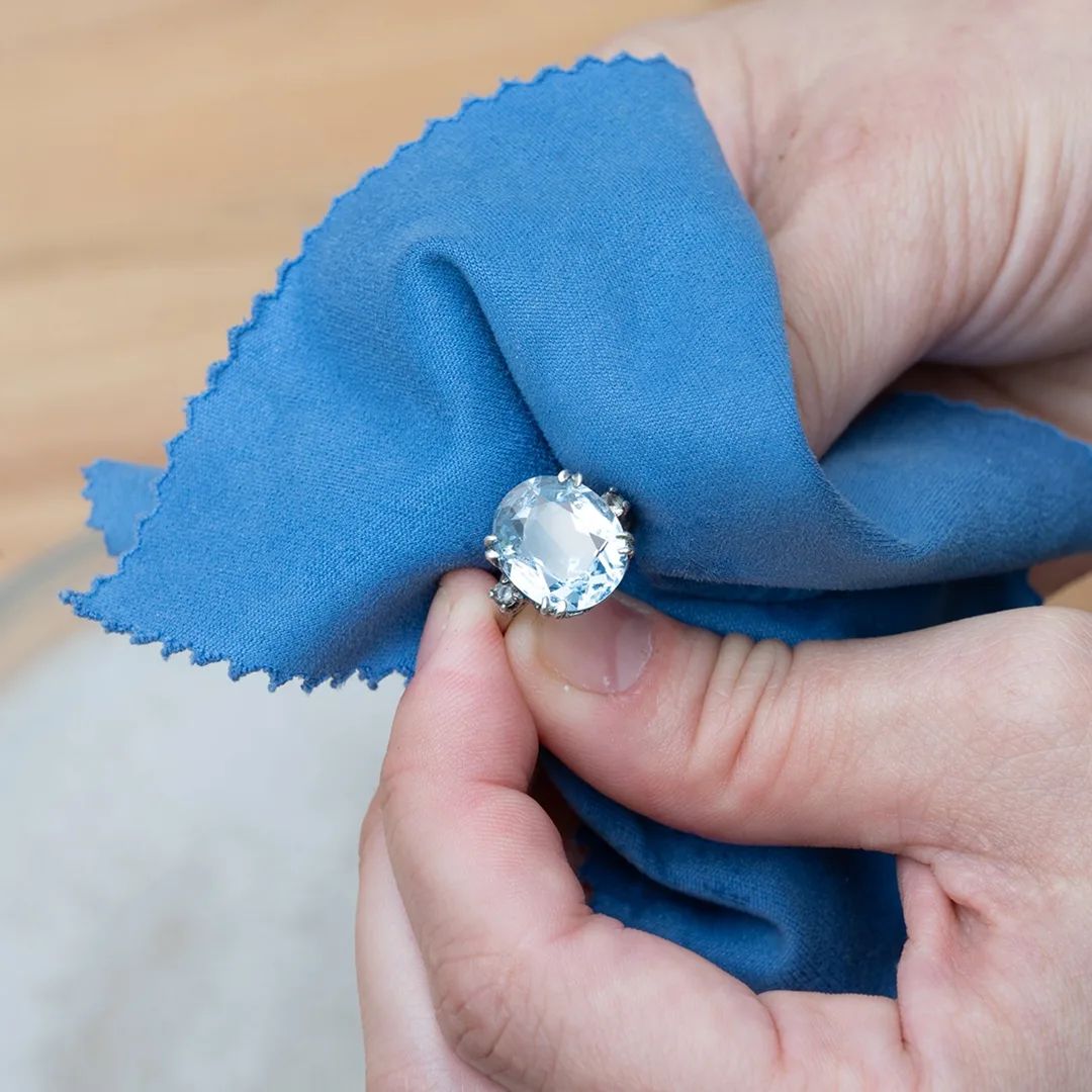 Hands polishing an engagement ring with a soft cloth — caring for gold jewelry by SAMA
