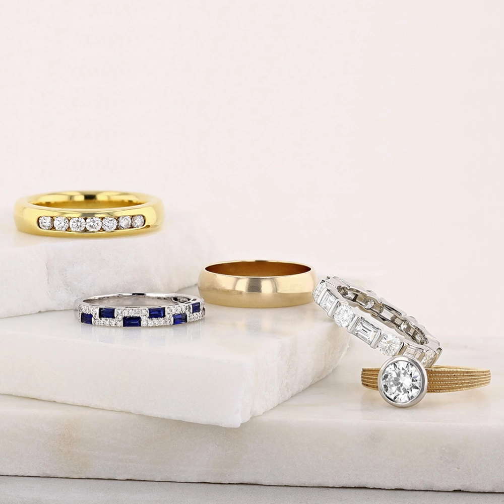 macro-shot-of-diamond-eternity-bands-and-engagement-rings-in-neutral-tones